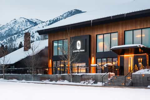 Modern mountain lodge with wood exterior and glass windows in snowy landscape