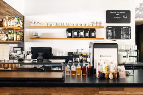 Modern coffee shop counter with shelving, espresso machine, and specialty drink menu board