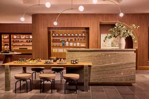 Luxury skincare boutique with wooden shelving, stone counter, organic product display, and modern pendant lighting