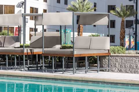 Pool lounge with modern gray cabanas and cushioned seating overlooking water