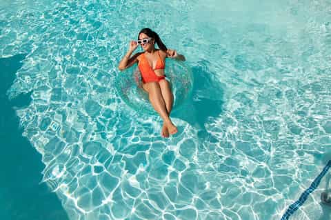 Woman floating on inflatable in crystal clear turquoise pool water