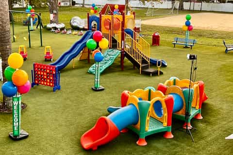 Colorful children's playground with slides, climbing structures, and play equipment on green lawn