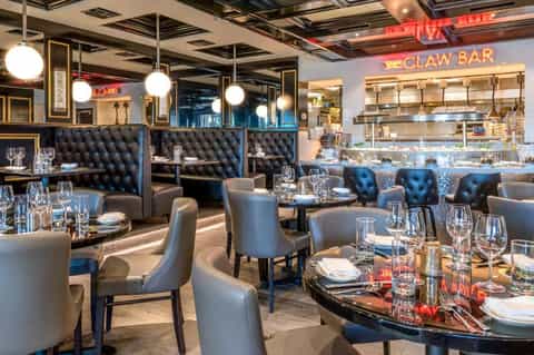 Upscale seafood restaurant interior with black tufted banquettes, modern lighting, and Claw Bar signage