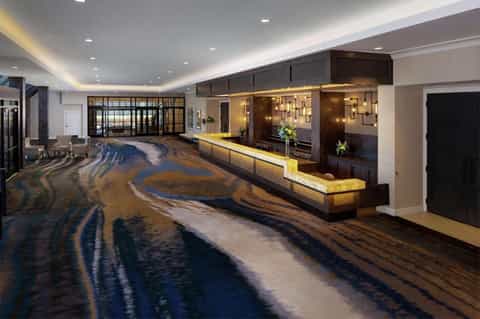 Hotel lobby with polished floors and illuminated reception desk against brown brick wall