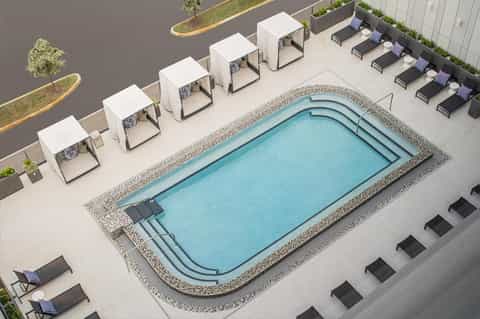 Aerial view of rectangular pool with white cabanas and lounge chairs on concrete deck