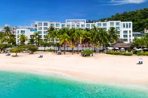 Beachfront resort with white modern buildings, palm trees, and turquoise ocean waters