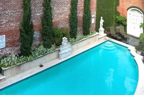 Rectangular swimming pool surrounded by ivy-covered brick walls