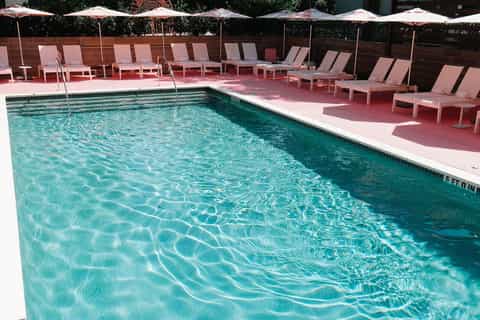 Resort pool with crystal-clear water surrounded by lounge chairs and umbrellas