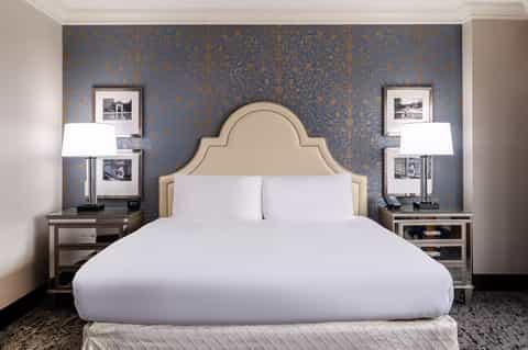 Elegant bedroom with cream upholstered headboard against blue damask wallpaper