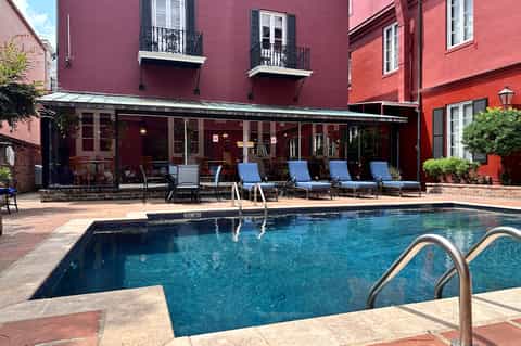 Indoor pool with blue lounge chairs facing a dark red colonial-style building with arched windows