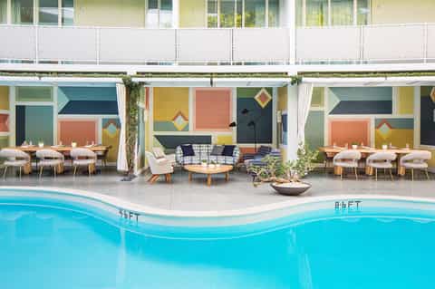 Modern poolside cabanas with colorful geometric wall art and lounge seating by turquoise pool
