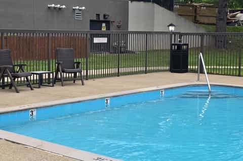 Outdoor swimming pool with blue water, concrete deck, black metal fencing, and lounge chairs