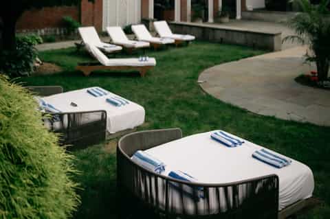 Luxury resort lawn with white loungers and blue-striped towels under shade structures