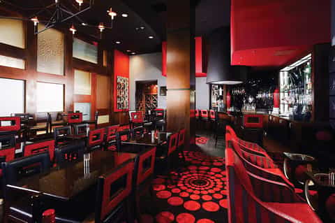 Modern restaurant interior with red and black décor, bar counter, and contemporary lighting