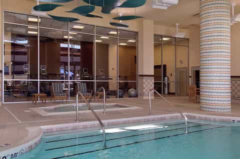 Indoor lap pool with lane dividers in modern hotel facility with glass walls and decorative ceiling elements