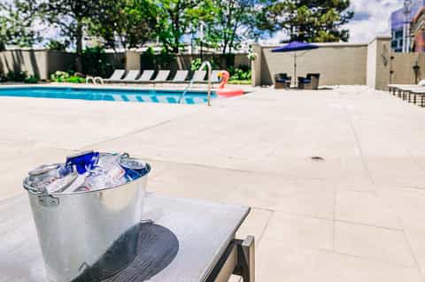 Resort pool area with lounge chairs, ice bucket on poolside table, and manicured landscaping
