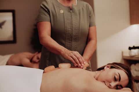 Spa therapist performing a back massage on a relaxed client in a treatment room