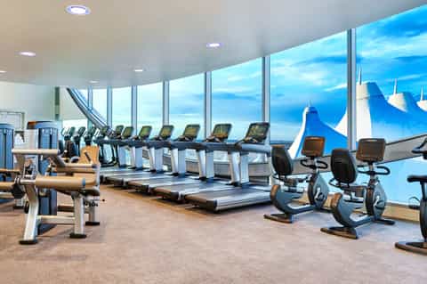 Fitness center with treadmills and exercise bikes overlooking mountains through floor-to-ceiling windows