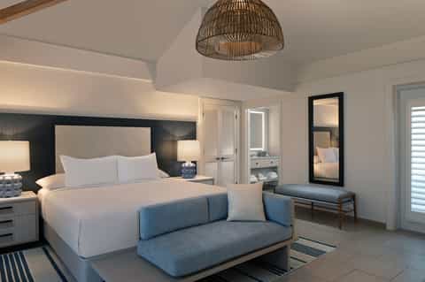 Luxury hotel bedroom with king bed, blue accent sofa, and contemporary furnishings