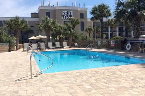 Hotel Hybee outdoor pool area with palm trees and lounge chairs under blue sky