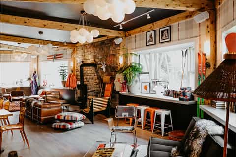 Mid-century modern lounge with exposed beams, fireplace, leather seating, and eclectic decor