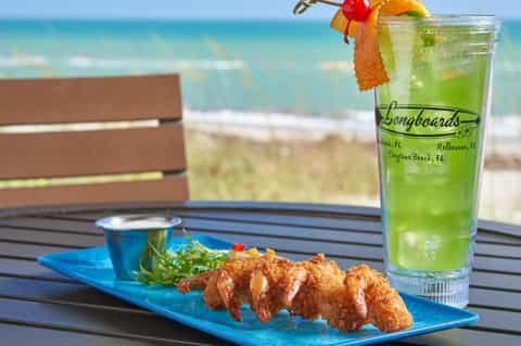 Fried shrimp platter with green cocktail and ocean view from beachfront dining table