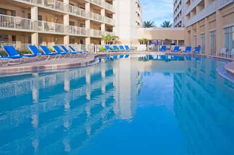 Indoor resort pool with crystal-clear blue water and blue lounge chairs surrounding the deck