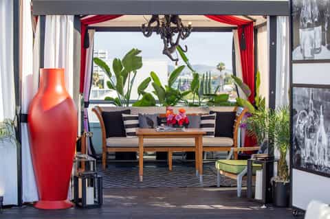 Modern resort lounge with red vase, striped seating, red curtains, and city view
