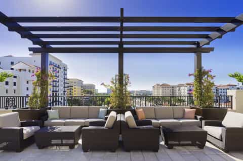 Rooftop lounge with black pergola, modern furniture, and city views with flowering plants