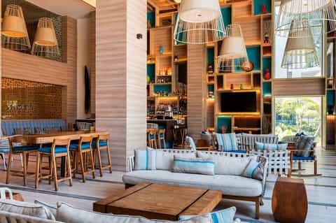 Modern hotel lobby with wooden shelving, blue accents, and stylish bar seating area