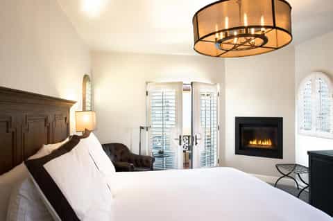 Luxurious hotel bedroom with fireplace, white bedding, and balcony doors