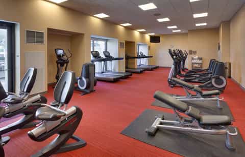 Fitness center with cardio equipment, treadmills, and exercise bikes on red carpet