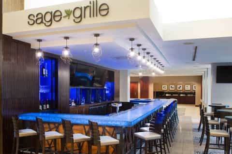 Modern upscale bar called Sage Grille with blue-lit counter, pendant lighting, and dark wood finishes
