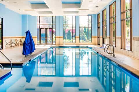 Indoor lap pool with blue water, large windows, and natural light in a bright facility