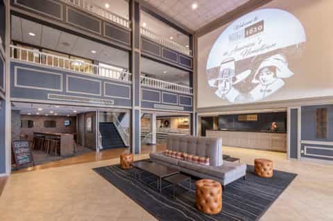 Historic hotel lobby with art deco design, vintage signage, leather seating, and two-story gallery space