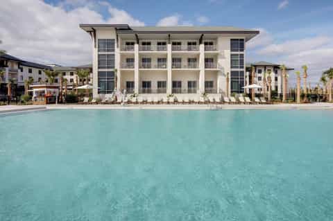 Beachfront resort building with white architecture and palm trees beside turquoise pool