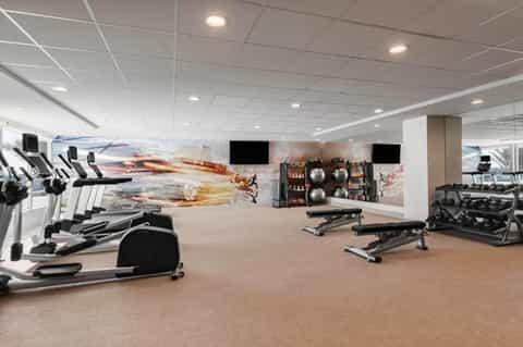 Fitness center with exercise equipment, treadmills, weights, and motivational wall graphics under ceiling lights