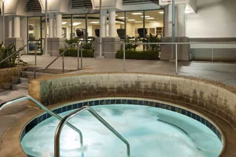Indoor spa facility with circular hot tub, arched architecture, glass walls, and modern office space