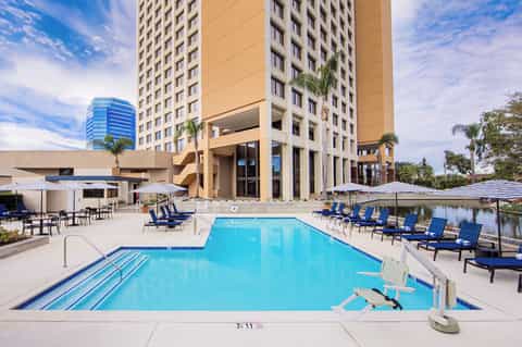 Large outdoor swimming pool with lap lanes, blue loungers, white umbrellas, and tall residential tower buildings