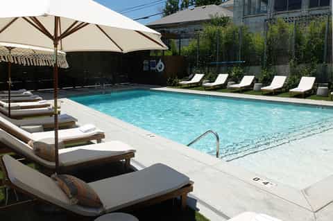 Resort pool with crystal blue water, lounge chairs with umbrellas, and manicured landscaping