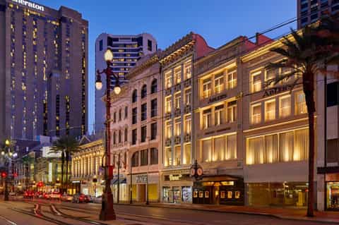 Historic downtown street at dusk with illuminated vintage buildings, palm trees, and modern hotel tower
