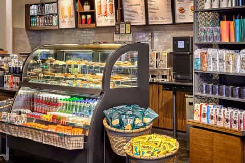 Bakery café display case with pastries, beverages, and merchandise on shelves
