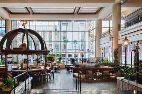 Luxurious hotel lobby atrium with sculptural art piece, multi-level seating areas, and expansive windows