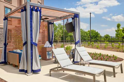 Outdoor lounge area with blue and white pergola, loungers, and landscaped grounds under clear sky