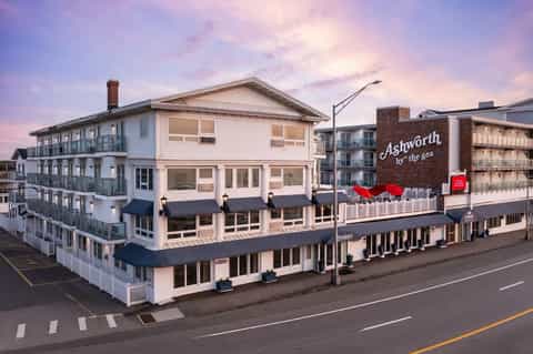 Historic beachfront hotel building with white railings at dusk with lit signage