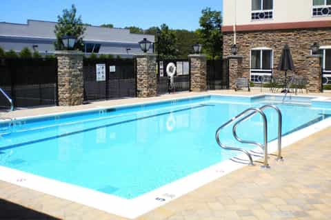 Outdoor swimming pool with metal railings and stone accent walls near residential buildings