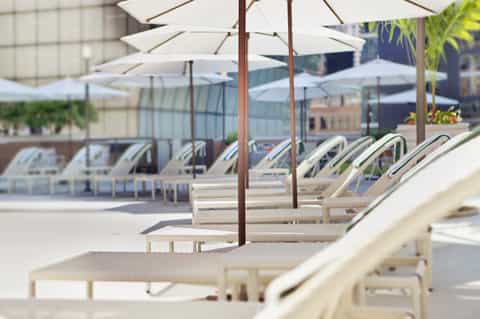 Pool deck with white umbrellas, lounge chairs, and modern furnishings