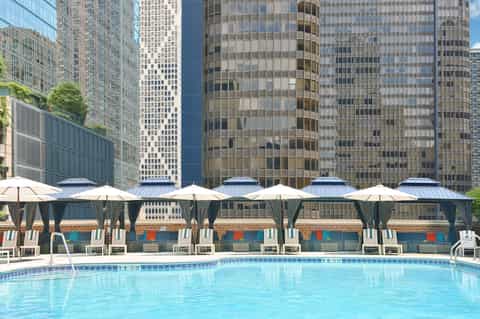 Rooftop pool with white cabanas overlooking downtown skyline with high-rise office buildings