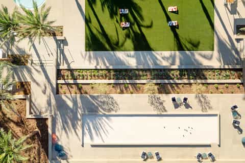 Aerial view of modern courtyard with green lawn, lounge chairs, and planted areas with shadows