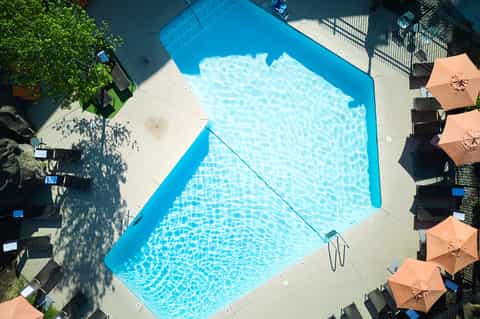 Aerial view of rectangular swimming pool with blue water and orange umbrellas on sun deck